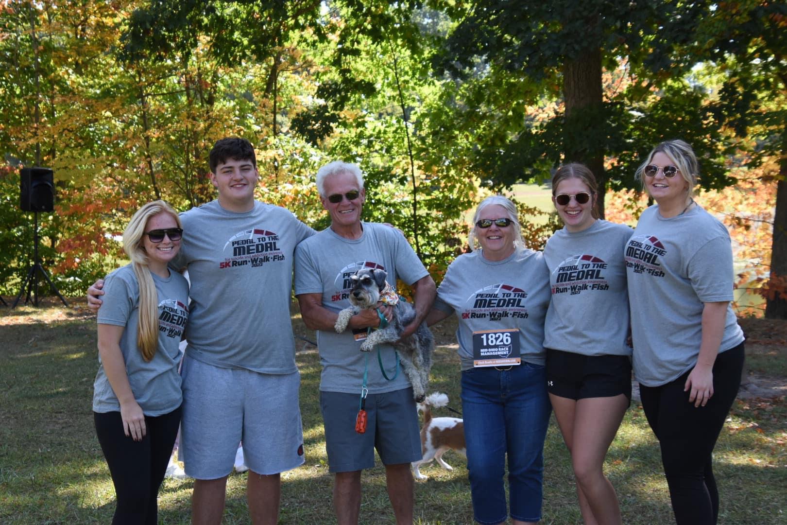 Grace, Owen, Rick, Maggie (dog), Julie, Joy, and Libby standing in front of Gross Lake